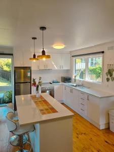 a kitchen with white cabinets and a white counter top at Sitara Cottage in Yanakie