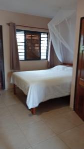 ein Schlafzimmer mit einem weißen Bett und einem Fenster in der Unterkunft Floh-Jo Tiny House in Paramaribo