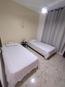 two beds in a room with white sheets at Double bed room in Santo Domingo