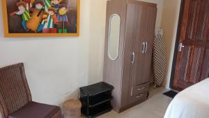 ein Schlafzimmer mit einem Schrank und einem Stuhl neben einem Bett in der Unterkunft Floh-Jo Tiny House in Paramaribo