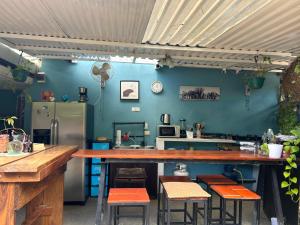 a kitchen with a counter with chairs and a refrigerator at The Backside House - Women Only - in Tamarindo +16 photos