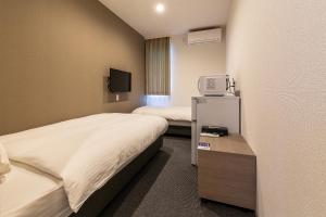 a hotel room with two beds and a tv at HOTEL R9 The Yard Sakai in Sakai