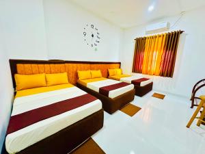 a bedroom with two beds and a window with a clock at Dreamy Homestay in Anuradhapura