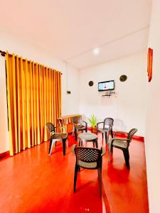 a room with chairs and tables and a flat screen tv at Dreamy Homestay in Anuradhapura