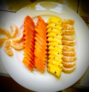 a white plate with slices of mango and other fruit at Dreamy Homestay in Anuradhapura
