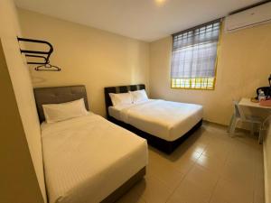 a bedroom with two beds and a desk and a window at Skudai Sojourn in Skudai