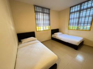a bedroom with two beds and two windows at Skudai Sojourn in Skudai +2 photos