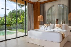 a bedroom with a large white bed and large windows at Sapta Cemagi - Villa Deluna in Cemagi +59 photos