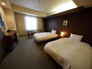 a hotel room with two beds and a desk at Nikko Station Hotel Classic in Nikko