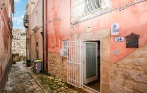 an alley with a pink building with a green door at Casa Herea in Ragusa