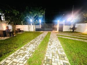 a walkway in a yard at night with lights at Golden Paradise Transit Hotel in Katunayaka