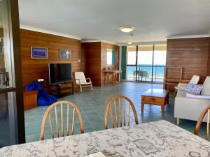 a living room with a table and chairs and a television at High Level with Ocean Views Everywhere in Buddina