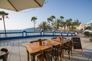 a restaurant with tables and chairs and a view of the ocean at Arguineguín Bay Apartments in La Playa de Arguineguín