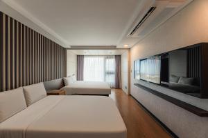 a hotel room with two beds and a flat screen tv at Hotel Air City Jeju in Jeju