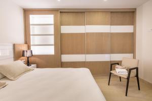 a bedroom with a white bed and a chair at Arguineguín Bay Apartments in La Playa de Arguineguín