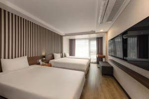 a hotel room with two beds and a flat screen tv at Hotel Air City Jeju in Jeju +34 photos