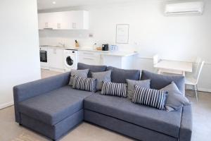 a blue couch with pillows in a living room at West Beach Lagoon 206 Ground Floor 2mins beach in Perth