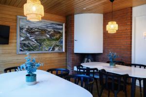 a restaurant with white tables and chairs and a painting at Hemavans Fjällcenter in Hemavan