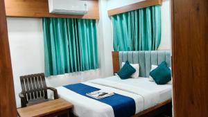 a bedroom with a bed with a chair and green curtains at Hotel New Vinayak in Ahmedabad +16 photos
