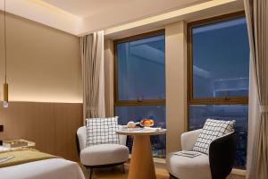 a hotel room with a bed and a table and chairs at Surprise Hotel Chengdu in Chengdu
