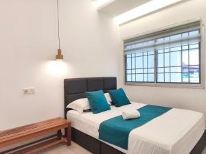 a bedroom with a bed with blue pillows and a window at Merdeka One Homestay 8pax 4Rooms in Sibu