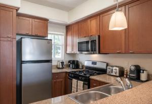 a kitchen with wooden cabinets and a stainless steel refrigerator at Modern 1 & 2 Bedroom Apartments Near Venice & MDR with Pool Gym & Cinema in Los Angeles +39 photos