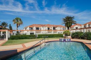 a swimming pool with palm trees and houses at The Breakers Yamba in Yamba