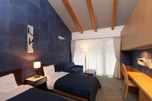 a hotel room with two beds and a blue wall at ウェルネスハウスさらい in Nomi