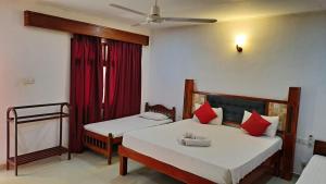 a bedroom with two beds with red pillows at Sea View Beach Hotel in Nilaveli