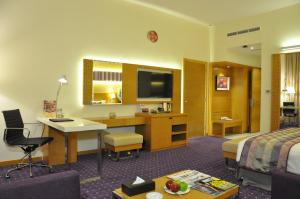 ドバイにあるフォーチュン パーク ホテルのデスクとベッドが備わるホテルルームです。