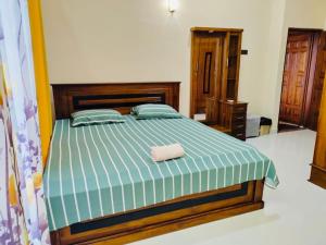 a bedroom with a bed with a green and white comforter at Scenic Lanka rooms in Dehiwala