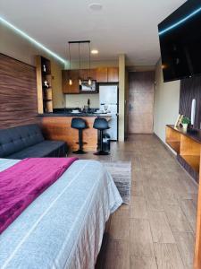 a bedroom with a large bed and a kitchen at Loft moderno y acogedor in Durango