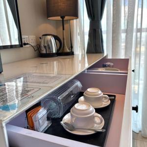 a kitchen counter with two cups and saucers at Grace Samudera Hotel in Semporna