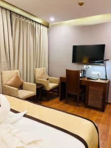 a hotel room with a bed and a desk and a television at Hotel Imperial Plaza Asansol in Āsansol