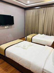 a hotel room with two beds and a flat screen tv at Hotel Imperial Plaza Asansol in Āsansol +62 photos