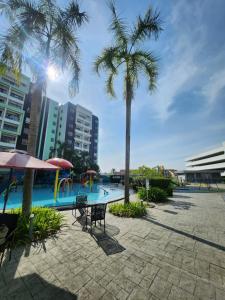 a swimming pool with palm trees and a playground at Manhattan Condominium Ipoh in Ipoh