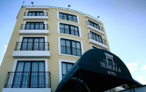 比亞維森西奧的住宿－Terraza Hotel Villavicencio，一座高大的黄色建筑,前面有标志