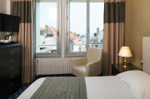 a hotel room with a bed and a chair and a window at Hotel Aguado in Dieppe