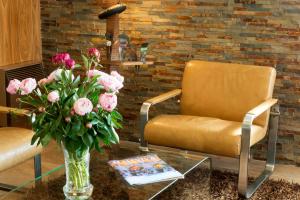 a vase of flowers on a glass table next to two chairs at Hotel Aguado in Dieppe