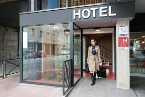 a woman is standing outside of a hotel at Hotel Aguado in Dieppe