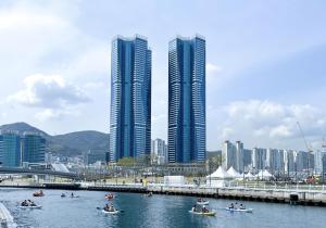 a group of people in boats in a river with tall buildings at Brown Suites Busan Station in Busan
