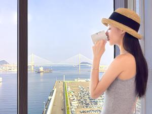 a woman in a hat taking a picture of a harbor at Brown Suites Busan Station in Busan