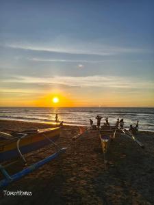 a group of people sitting on a beach at sunset at Duplex A- Seaside Haven Transient Inn at Caba, La Union in Caba
