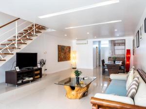 a living room with a couch and a tv and stairs at Townhouse Six9 The Pool Residence in Koh Samui