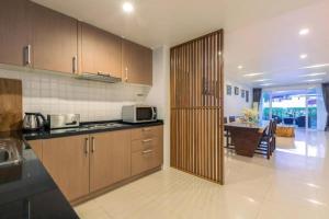 a kitchen with wooden cabinets and a table in it at Townhouse Six9 The Pool Residence in Koh Samui