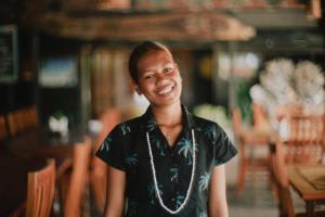 a woman wearing a necklace smiles at the camera at Golden Point Resort in Rakiraki