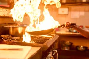 a person cooking food in a pan on a stove at Golden Point Resort in Rakiraki