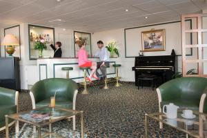 a couple sitting at a bar in a waiting room with a piano at Hotel Aguado in Dieppe