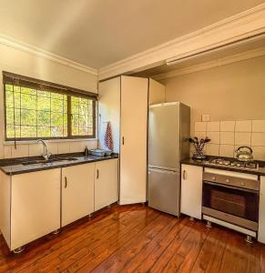 a kitchen with a stainless steel refrigerator and wooden floors at Magoebaskloof Getaway in Magoebaskloof