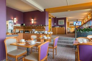 a restaurant with purple walls and wooden tables and chairs at Hotel Aguado in Dieppe
